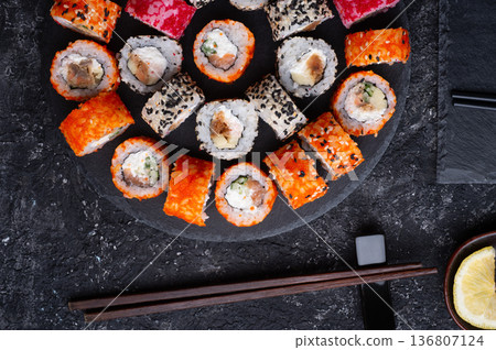 different delicious sushi rolls set with fish beautiful served at black dish at black table. flat lay. close up different delicious sushi rolls set with fish beautiful served at black dish at black table. flat lay. close up 136807124