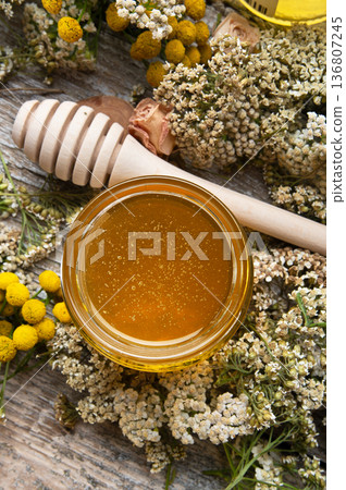 fresh natual linden honey in small glass jar with wooden  honey spoon around herb flowers. flat lay. close up 136807245