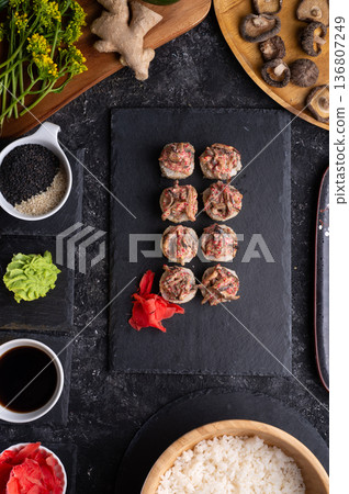 sushi roll with shiitake mushrooms served at black dish with rise at black table. flat lay sushi roll with shiitake mushrooms served at black dish with rise at black table. flat lay 136807249