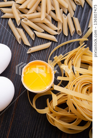 different shape of italian pasta with eggs on dark wooden table. cooking  background. close up 136807475