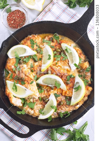 Haddock fish piccata with lemon and capers in cast iron pan, vertical, top view closeup Haddock fish piccata with lemon and capers in cast iron pan, vertical, top view closeup 136808033
