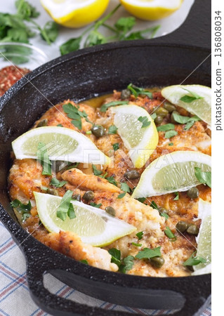 Delicious haddock fish piccata with lemon and capers in cast iron pan, vertical 136808034