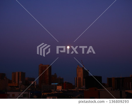 一輪滿月從一排公寓樓上升起。 136809293