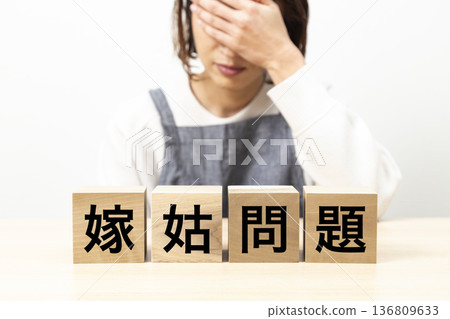 A woman wearing an apron and a block with the words "mother-in-law and daughter-in-law problems" written on it A woman wearing an apron and a block with the words "mother-in-law and daughter-in-law problems" written on it 136809633