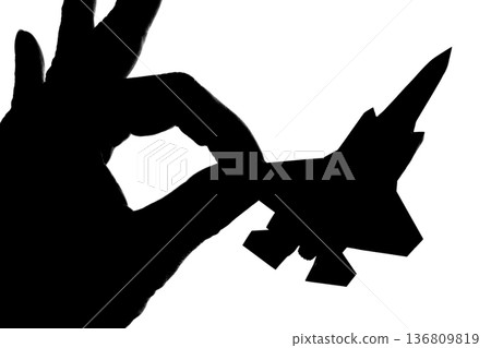 一架噴射戰鬥機的輪廓，被手指夾在中間。 136809819