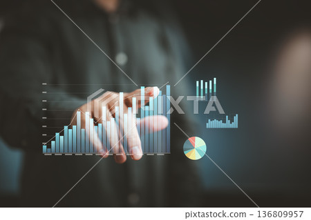 Businessman interacting with virtual data charts and graphs on transparent screen Businessman interacting with virtual data charts and graphs on transparent screen 136809957