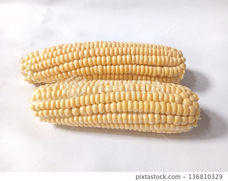 Two fresh corn cobs with pale yellow kernels, tightly packed and ripe, perfect for agriculture and culinary use. Two fresh corn cobs with pale yellow kernels, tightly packed and ripe, perfect for agriculture and culinary use. 136810329