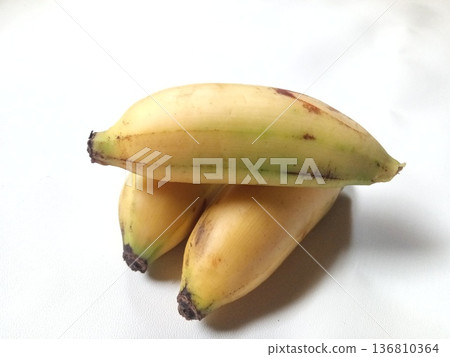 Three ripe tropical bananas with yellow peels and natural spots, fresh and perfect for healthy eating Three ripe tropical bananas with yellow peels and natural spots, fresh and perfect for healthy eating 136810364