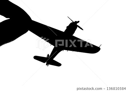 Silhouette of a propeller fighter plane pinched between fingers 136810384