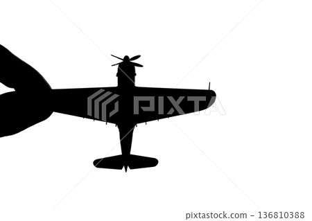 Silhouette of a propeller fighter plane pinched between fingers 136810388