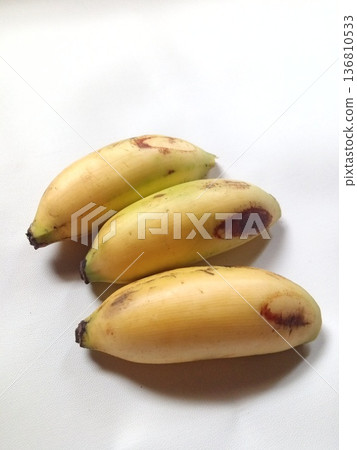 Three ripe bananas with yellow peels and natural brown spots, tropical fruit perfect for healthy eating and cooking Three ripe bananas with yellow peels and natural brown spots, tropical fruit perfect for healthy eating and cooking 136810533