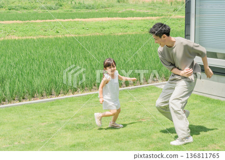 Parent and child, dad and daughter playing tag on the lawn of their home Parent and child, dad and daughter playing tag on the lawn of their home 136811765