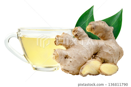 Fresh ginger root, slices, and green leaves next to a clear glass cup of hot herbal tea isolated. Healthy drink and natural remedy concept for wellness and immune support. 136811790