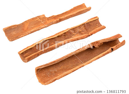 Three dried cinnamon bark sticks isolated. High quality aromatic spice for cooking, baking, and health. Close up view of natural cassia cinnamon pieces for food design. 136811793