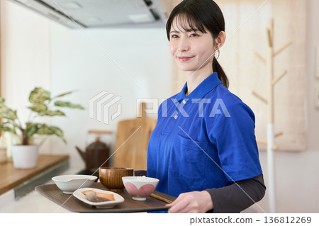 A caregiver providing meal support during a home care visit 136812269