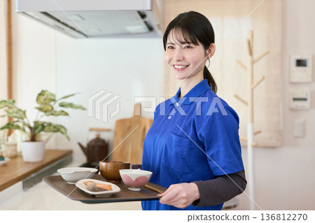 A caregiver providing meal support during a home care visit A caregiver providing meal support during a home care visit 136812270