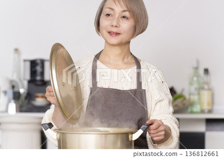 A senior woman making pork soup in the kitchen and serving it in a bowl 136812661