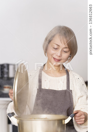 A senior woman making pork soup in the kitchen and serving it in a bowl 136812663