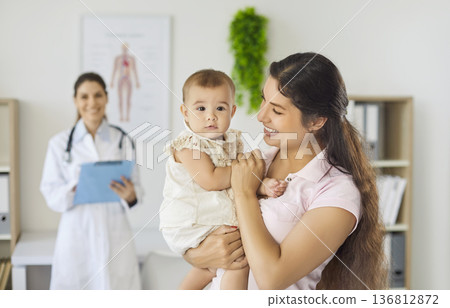 Mother holding baby after pediatric checkup with doctor in modern clinic Mother holding baby after pediatric checkup with doctor in modern clinic 136812872