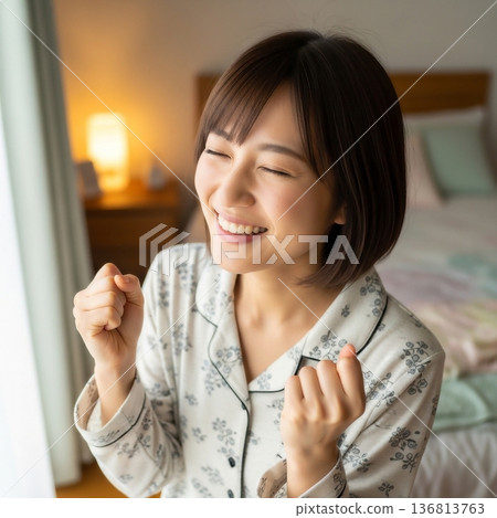 一位年輕女子在臥室裡面帶著微笑，揮舞著拳頭。 136813763