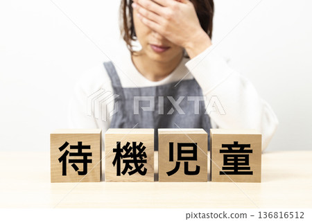 一位身穿圍裙、手持寫有「托兒所等候名單」字樣積木的女士 一位身穿圍裙、手持寫有「托兒所等候名單」字樣積木的女士 136816512