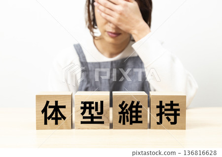 一位身穿圍裙、手持寫著「保持身材」字樣的方塊的女士 一位身穿圍裙、手持寫著「保持身材」字樣的方塊的女士 136816628