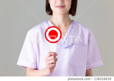 一位身穿醫用工作服的中年女護士,手裡拿著一個圓盤。 一位身穿醫用工作服的中年女護士,手裡拿著一個圓盤。 136816639