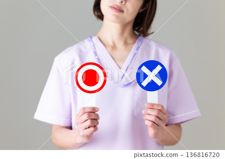 A middle-aged female nurse in a medical scrub holding a rounded plate and worrying A middle-aged female nurse in a medical scrub holding a rounded plate and worrying 136816720