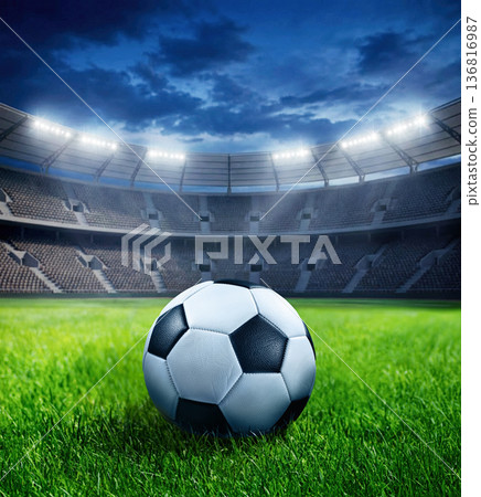 Ball on Silent football arena with glowing floodlights and vibrant grass surface 136816987
