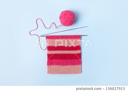 Pink knitted wool on blue background with knitting needles for knitting warm clothes and hobbies needlework Pink knitted wool on blue background with knitting needles for knitting warm clothes and hobbies needlework 136817913