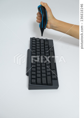 A person using a blower to clean a keyboard 136818146