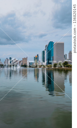 evening panorama of Bangkok city skyline with skyscrapers and Benchakitti park lake, vibrant cityscape view with reflections over pond water at dusk evening panorama of Bangkok city skyline with skyscrapers and Benchakitti park lake, vibrant cityscape view with reflections over pond water at dusk 136820145