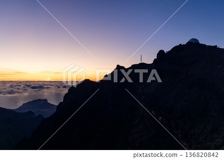 Soft sunrise lights mountain ridges at Miradouro do Pico do Areiro as clouds fill valleys below 136820842