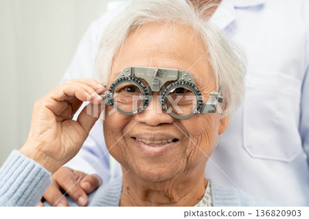 Optometrist checking Asian elderly woman ophthalmic vision eye test and using optical trial frame. Optometrist checking Asian elderly woman ophthalmic vision eye test and using optical trial frame. 136820903