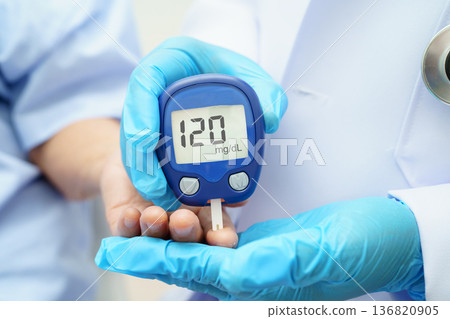 Asian doctor using digital glucose meter for check sample blood sugar level to treatment diabetes. Asian doctor using digital glucose meter for check sample blood sugar level to treatment diabetes. 136820905