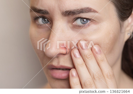 woman suffers and experiences pain from a nose piercing.. Inflamed piercing, nose after piercing. Red nose piercing site. Close up photo woman suffers and experiences pain from a nose piercing.. Inflamed piercing, nose after piercing. Red nose piercing site. Close up photo 136821664