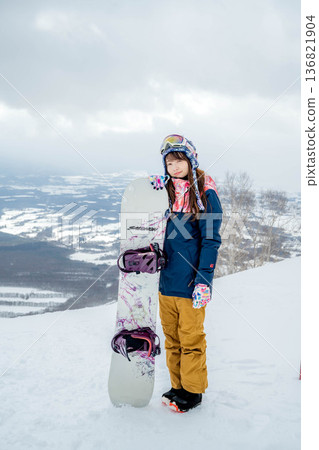 Young woman snowboarding at the top of the slope Young woman snowboarding at the top of the slope 136821904