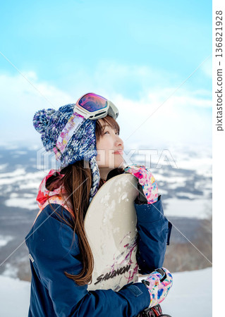 Young woman snowboarding at the top of the slope Young woman snowboarding at the top of the slope 136821928