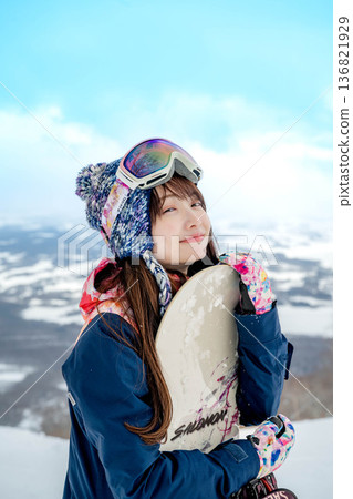 Young woman snowboarding at the top of the slope 136821929