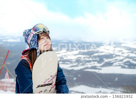 Young woman snowboarding at the top of the slope Young woman snowboarding at the top of the slope 136821932