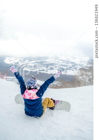 Young woman snowboarding at the top of the slope 136821949