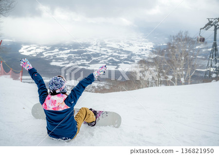 Young woman snowboarding at the top of the slope 136821950