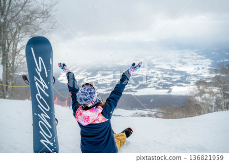 Young woman snowboarding at the top of the slope 136821959