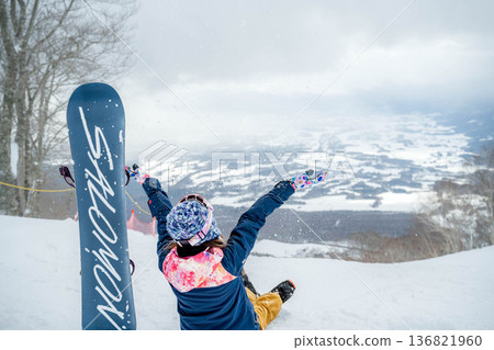 Young woman snowboarding at the top of the slope 136821960