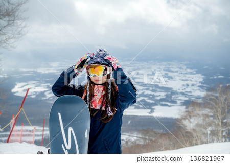 Young woman snowboarding at the top of the slope Young woman snowboarding at the top of the slope 136821967