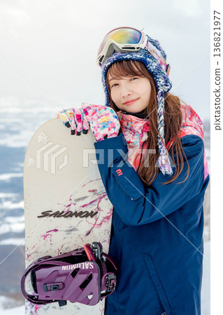 Young woman snowboarding at the top of the slope Young woman snowboarding at the top of the slope 136821977
