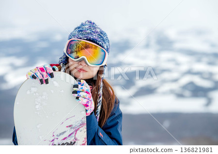 Young woman snowboarding at the top of the slope 136821981