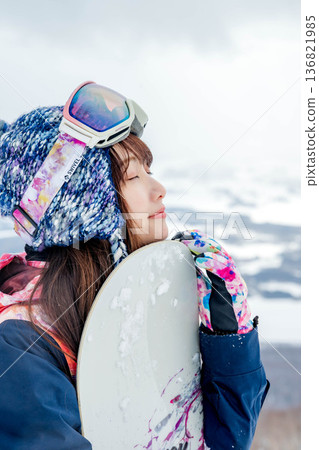 Young woman snowboarding at the top of the slope 136821985