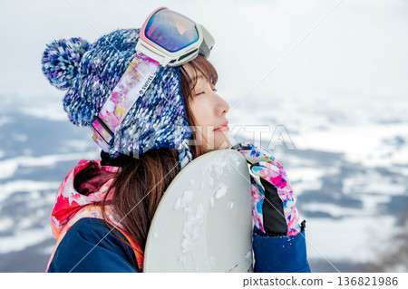 Young woman snowboarding at the top of the slope 136821986