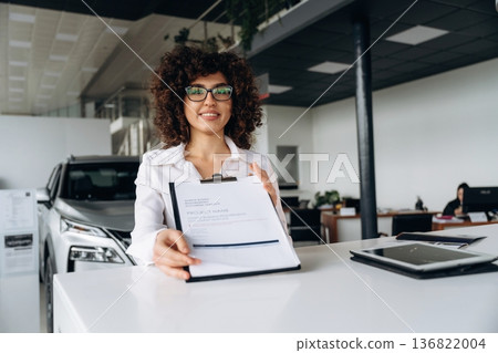 Fulfill the document of buying. Female employee is in the car retail shop Fulfill the document of buying. Female employee is in the car retail shop 136822004